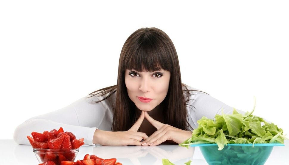 Frau am Tisch mit Kräutern und Erdbeeren